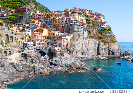 Multicolored houses on cliff edge. Manarola Italian village Cinque Terre, Liguria, Italy. Summer sea vacation Multicolored houses on cliff edge. Manarola Italian village Cinque Terre, Liguria, Italy. Summer sea vacation 133582884