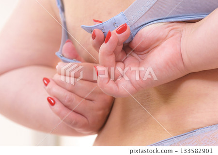 Woman back view putting on her bra lingerie. 133582901