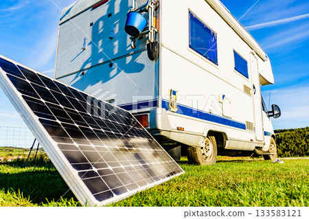 Camper with portable solar panel on coast 133583121