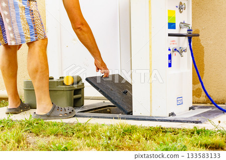 Man emptying caravan tank toilet cassette in dump station. 133583133