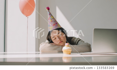 Sleepy Birthday Party Moment Woman in Party Hat Resting at Desk with Cupcake and Laptop 133583169
