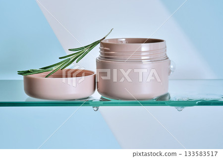A jar of rosemary cream on the glass shelf of the bathroom. 133583517