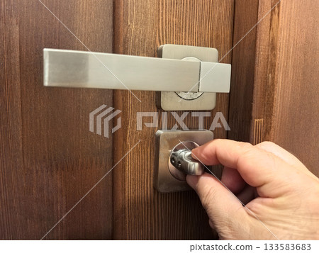 Unlocking a secure door with a modern handle in a cozy environment Unlocking a secure door with a modern handle in a cozy environment 133583683