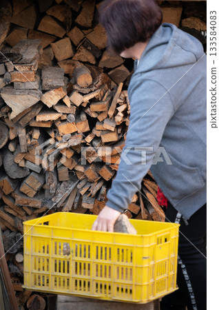 Woman collecting firewood on a crisp autumn afternoon, enjoying the peaceful surroundings and preparing for cozy evenings by the fireplace Woman collecting firewood on a crisp autumn afternoon, enjoying the peaceful surroundings and preparing for cozy evenings by the fireplace 133584083