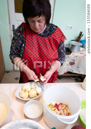 Preparing fresh apple slices for a delicious dessert in a cozy kitchen setting filled with warm colors and homely charm during a sunny afternoon Preparing fresh apple slices for a delicious dessert in a cozy kitchen setting filled with warm colors and homely charm during a sunny afternoon 133584089