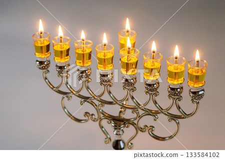Bright candles glow in beautiful menorah, creating warm atmosphere for Hanukkah event celebration Bright candles glow in beautiful menorah, creating warm atmosphere for Hanukkah event celebration 133584102
