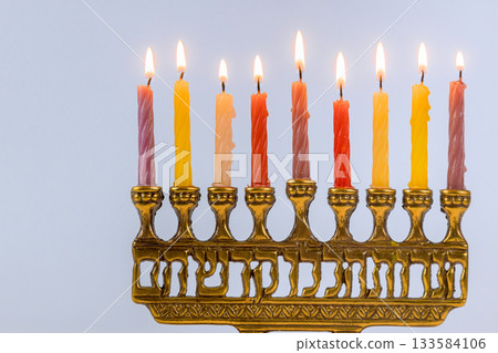 Glowing Hanukkah candles glow on menorah, creating warm atmosphere during Jewish festive event celebrating traditions. 133584106