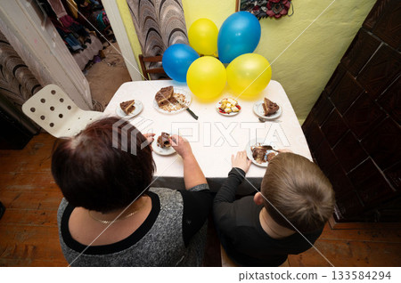 Celebration of togetherness with cake and laughter during a cozy indoor gathering in a colorful space filled with balloons Celebration of togetherness with cake and laughter during a cozy indoor gathering in a colorful space filled with balloons 133584294
