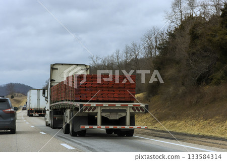 Truck loaded with wooden pallets drives on quiet American highway 133584314