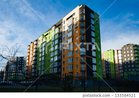 Vibrant modern apartments stand tall against a clear blue sky in a bustling neighborhood filled with life and activity Vibrant modern apartments stand tall against a clear blue sky in a bustling neighborhood filled with life and activity 133584521