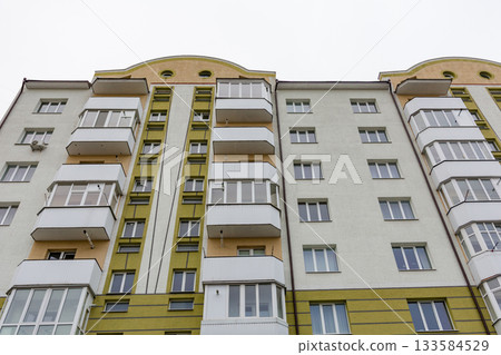 Modern apartment building showcasing distinctive architecture and clean lines in an urban setting on a cloudy day Modern apartment building showcasing distinctive architecture and clean lines in an urban setting on a cloudy day 133584529