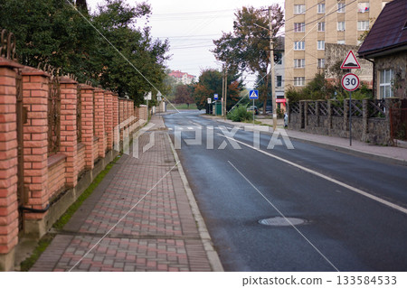 Quiet street at dawn with a cobblestone sidewalk and brick walls in a peaceful neighborhood setting Quiet street at dawn with a cobblestone sidewalk and brick walls in a peaceful neighborhood setting 133584533