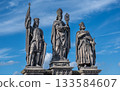 Prague, czech republic, august 9, 2023. Baroque sandstone statues of saints, including norbert, wenceslaus, and sigismund, standing against a blue sky on prague's charles bridge 133584607