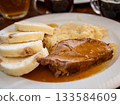 Prague, czech republic, august 9, 2023. Plate with classic czech meal, enjoying roasted pork with gravy, sliced bread dumplings for dinner 133584609