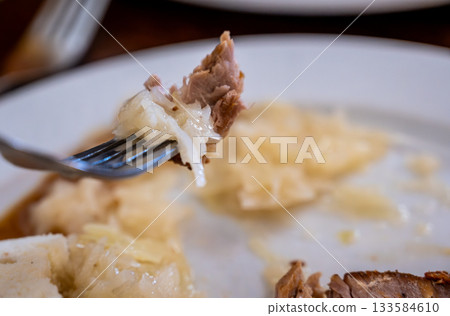 Prague, czech republic, august 9, 2023. Fork with tender roasted pork, tangy white cabbage sauerkraut and fluffy dumplings czech comfort meal close-up Prague, czech republic, august 9, 2023. Fork with tender roasted pork, tangy white cabbage sauerkraut and fluffy dumplings czech comfort meal close-up 133584610