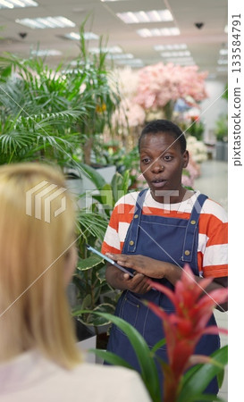 Florist assisting customer choosing plants in flower shop Florist assisting customer choosing plants in flower shop 133584791