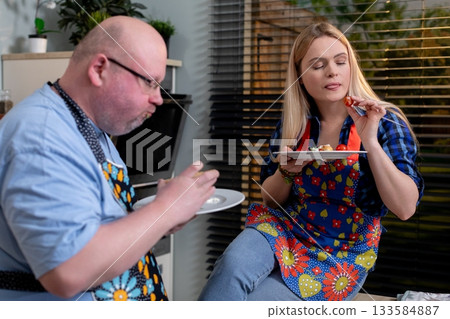 A Culinary Duo Happily Enjoying a Meal Together While Wearing Colorful and Fun Aprons A Culinary Duo Happily Enjoying a Meal Together While Wearing Colorful and Fun Aprons 133584887