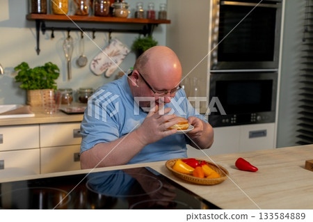 A Cooking Enthusiast Who is Fully Enjoying a Delicious Meal in a Modern Kitchen Setting 133584889