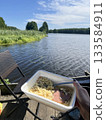 Instant noodles in plastic bowl by lake, outdoor camping lunch 133584911
