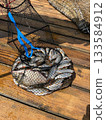 Full fishing catch in landing net on wooden pier in summer 133584912