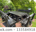 Rustic wooden garden table with benches under green pergola 133584918