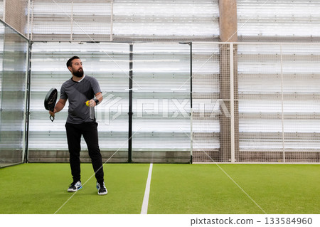 Young hispanic male playing padel tennis in indoor court Young hispanic male playing padel tennis in indoor court 133584960