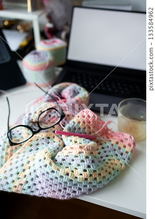 Crochet project with glasses and laptop on workspace desk 133584962