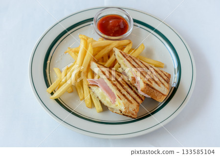 Ham and cheese hot sandwich and plate of french fries 133585104