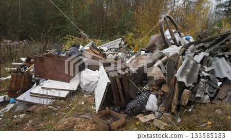 abandoned metal debris, rusty scrap amid neglected surroundings, decaying objects scattered across overgrown terrain, wornout appliances and metal remnants in forgotten urban space 133585183