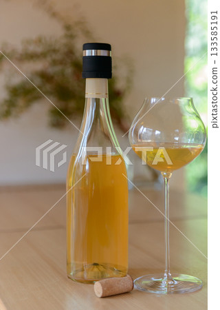 Close-up of a bottle of natural orange wine and a wine glass 133585191