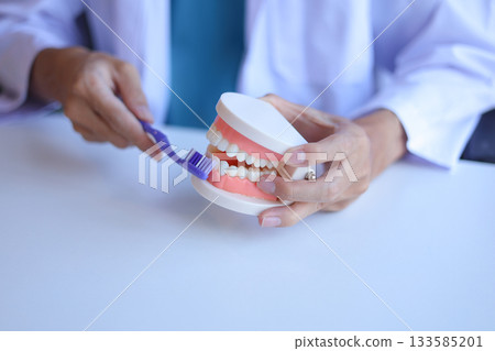 Dentist demonstrates how to brush teeth correctly. 133585201