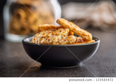 Crunchy salted crackers in bowl on black table. 133585472