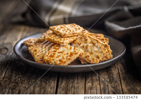 Crunchy salted crackers on plate on wooden table. Crunchy salted crackers on plate on wooden table. 133585474
