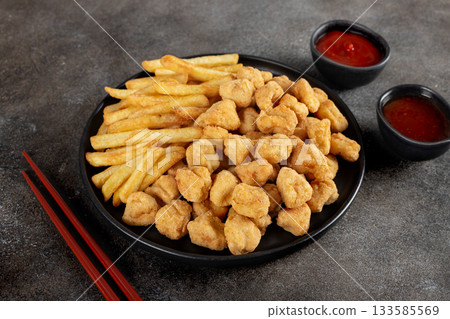 Crispy popcorn chicken and French fries with ketchup and chili sauce on gray background. Fast food combo meal. 133585569