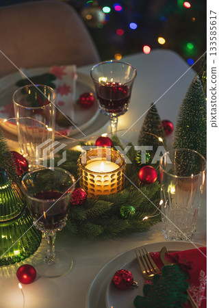 Festive Holiday Table Setting with Candle Lifghts and Decorations against Christmas Tree 133585617