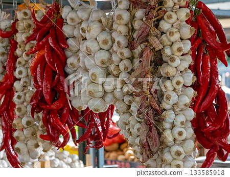 Garlic and peppers hanging on market stall Garlic and peppers hanging on market stall 133585918