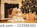 Happy children, little girls playing, gift box, Christmas tree, fireplace with holiday light at home 133586301