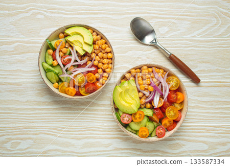 Two bowls with vibrant vegetarian chickpea salad with fresh vegetables in ceramic bowls top view Two bowls with vibrant vegetarian chickpea salad with fresh vegetables in ceramic bowls top view 133587334