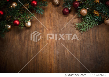 Christmas Decorations on Wood. Festive pine branches and baubles on a wooden surface. 133587662