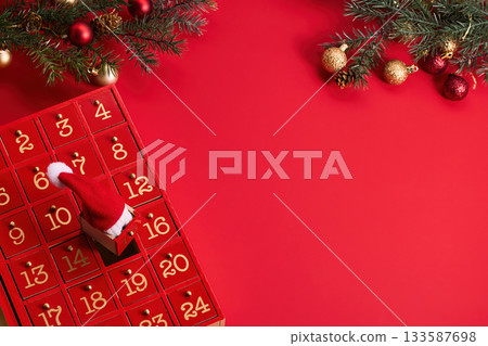 Festive Advent Calendar. Red advent calendar and Christmas decor on a vibrant red background. 133587698