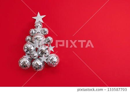 Festive Christmas Tree. A Christmas tree made of silver ornaments and stars on a vibrant red background. 133587703