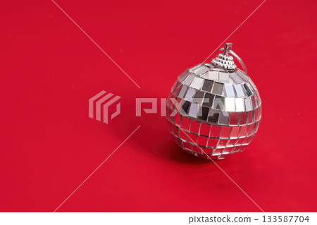 Single Disco Ball. A shiny silver disco ball on a vibrant red background. 133587704