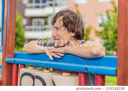A man playing with his small son on a playground, laughing and engaging in active fun together in a bright outdoor setting. Family bonding, early childhood development and healthy outdoor lifestyle A man playing with his small son on a playground, laughing and engaging in active fun together in a bright outdoor setting. Family bonding, early childhood development and healthy outdoor lifestyle 133588188