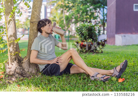 A man relaxing in a park on a sunny day, sitting peacefully on the grass and enjoying nature in a calm outdoor setting. Leisure time, mindfulness, mental wellness and slow living lifestyle concept A man relaxing in a park on a sunny day, sitting peacefully on the grass and enjoying nature in a calm outdoor setting. Leisure time, mindfulness, mental wellness and slow living lifestyle concept 133588216