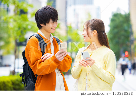 Young men and women looking at smartphones in the city Young men and women looking at smartphones in the city 133588558