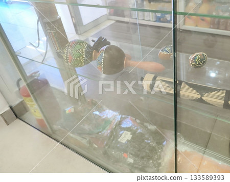 Colorful maracas displayed in a glass cabinet, featuring intricate geometric and dotted patterns in various hues on dark backgrounds. Retail, shop Colorful maracas displayed in a glass cabinet, featuring intricate geometric and dotted patterns in various hues on dark backgrounds. Retail, shop 133589393