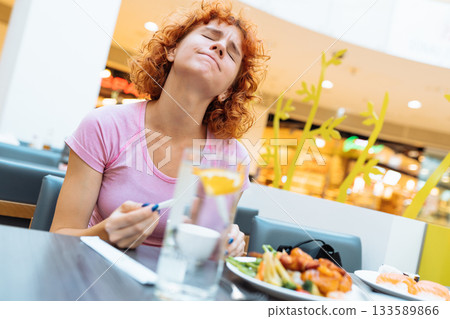 attractive redhead teen girl eating chinese soup in fast food restaurant 133589866