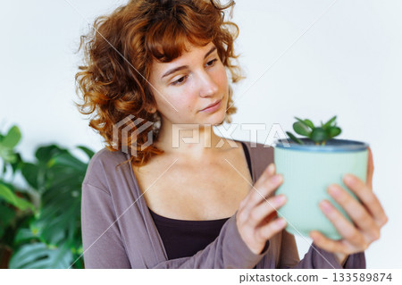 young girl holds flowerpot with plant in hands 133589874