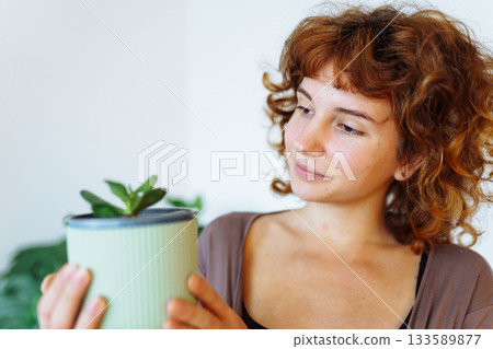 young girl holds flowerpot with plant in hands 133589877