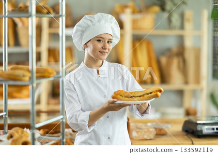 Young woman chef of pastry shop demonstrates product of assortment, bocadillo on disposable plates 133592119